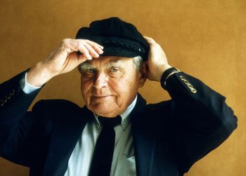 Na zdjęciu znajduje się Czesław Miłosz, który ma ubraną czapkę i trzyma ją rękoma