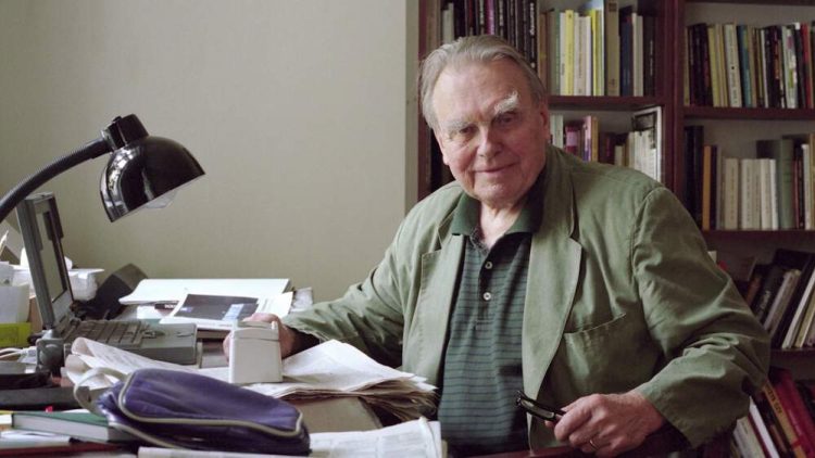 Na zdjęciu znajduje się Czesław Miłosz, który siedzi przy biurku