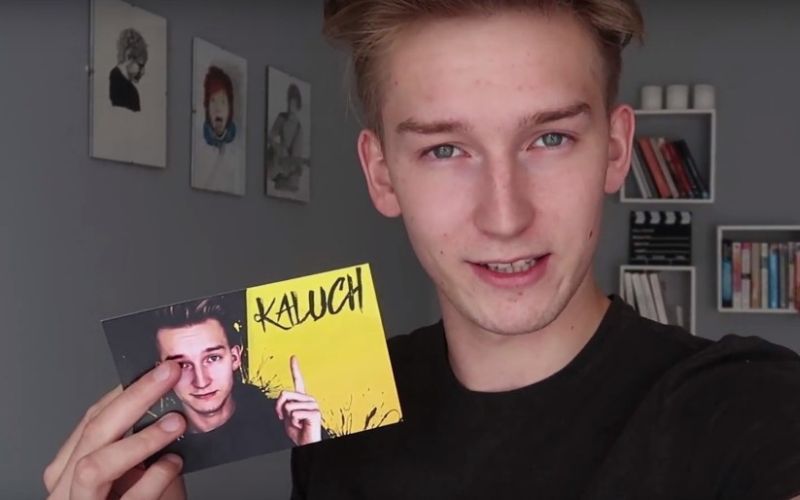 Na zdjęciu znajduje się Kaluch w wieku nastoletnim, który trzyma w ręce żółtą karteczkę.