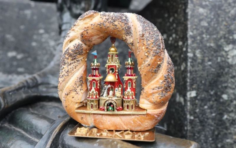 Na zdjęciu znajduje się obwarzanek krakowski, a obok niego szopka krakowska