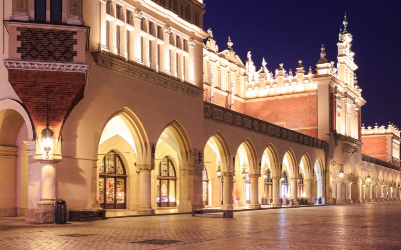 Zdjęcie przedstawia oświetlony budynek Sukiennic w Krakowie