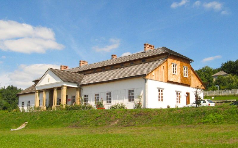 Zdjęcie przedstawia dwór z drogini z zewnętrz