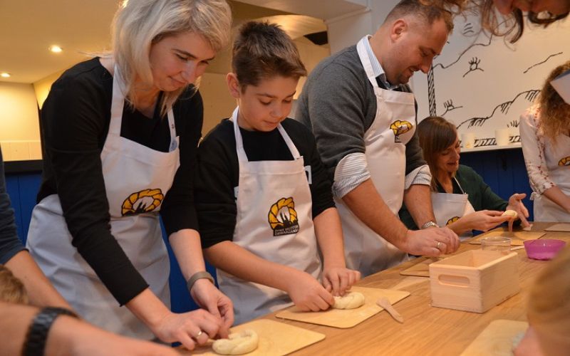 Zdjęcie przedstawia rodziców z dzieckiem podczas warsztatów w Żywe Muzeum Obwarzanka w Krakowie