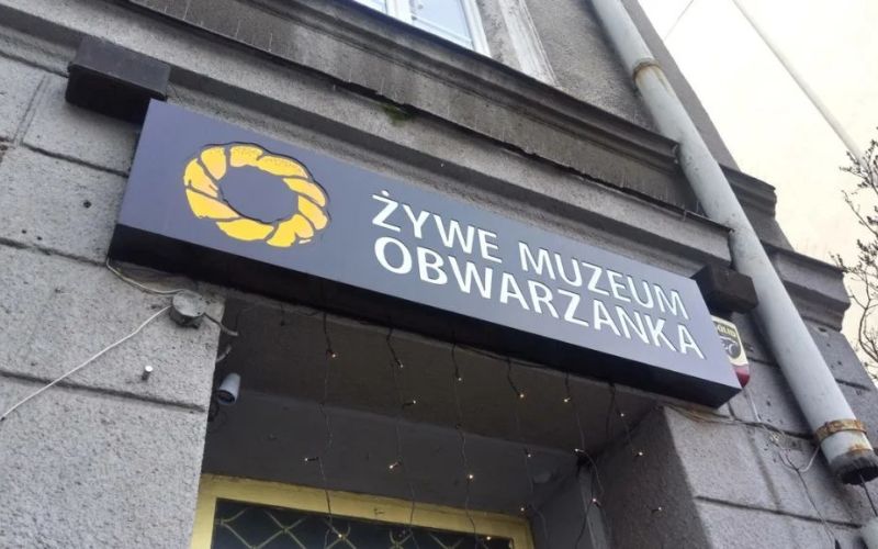 Zdjęcie przedstawia szyld Żywe Muzeum Obwarzanka przed wejściem do budynku