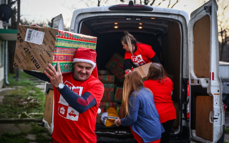 Zdjęcie przedstawia wolontariuszy szlachetnej paczki, którzy przenoszą paczki z samochodu