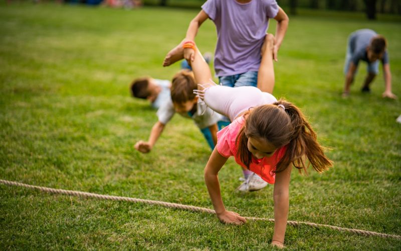 Zdjęcie przedstawia bawiące się dzieci na trawie