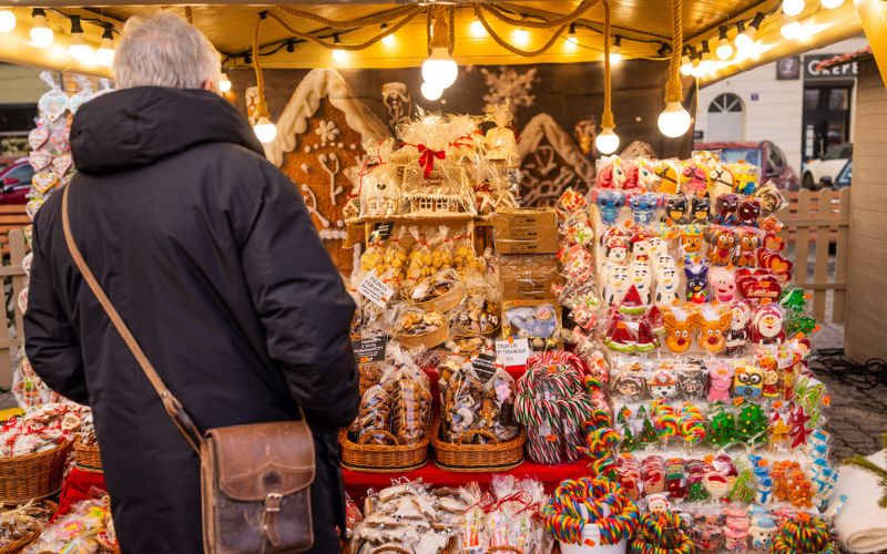 Zdjęcie przedstawia stoisko z rękodziełem na jarmarku, przy którym stoi kobieta