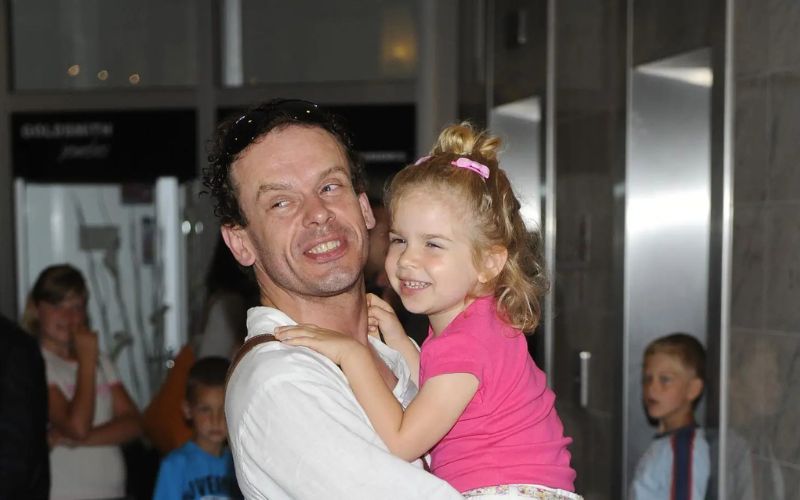 Zdjęcie przedstawia Tomasza Schimscheinera, który trzyma swoją córkę na rękach