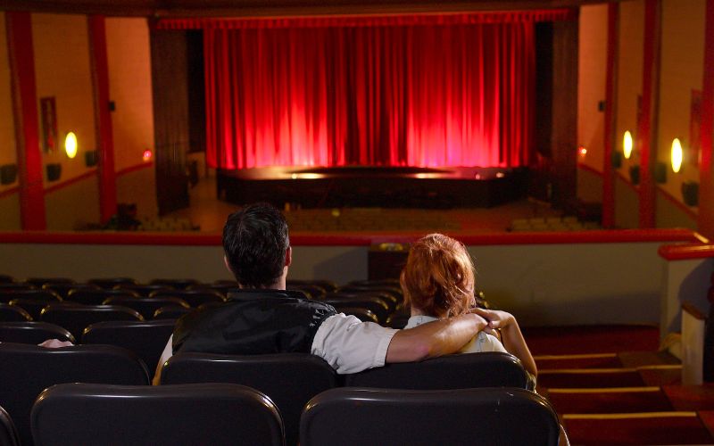 Zdjęcie przedstawia parę, która siedzi w teatrze