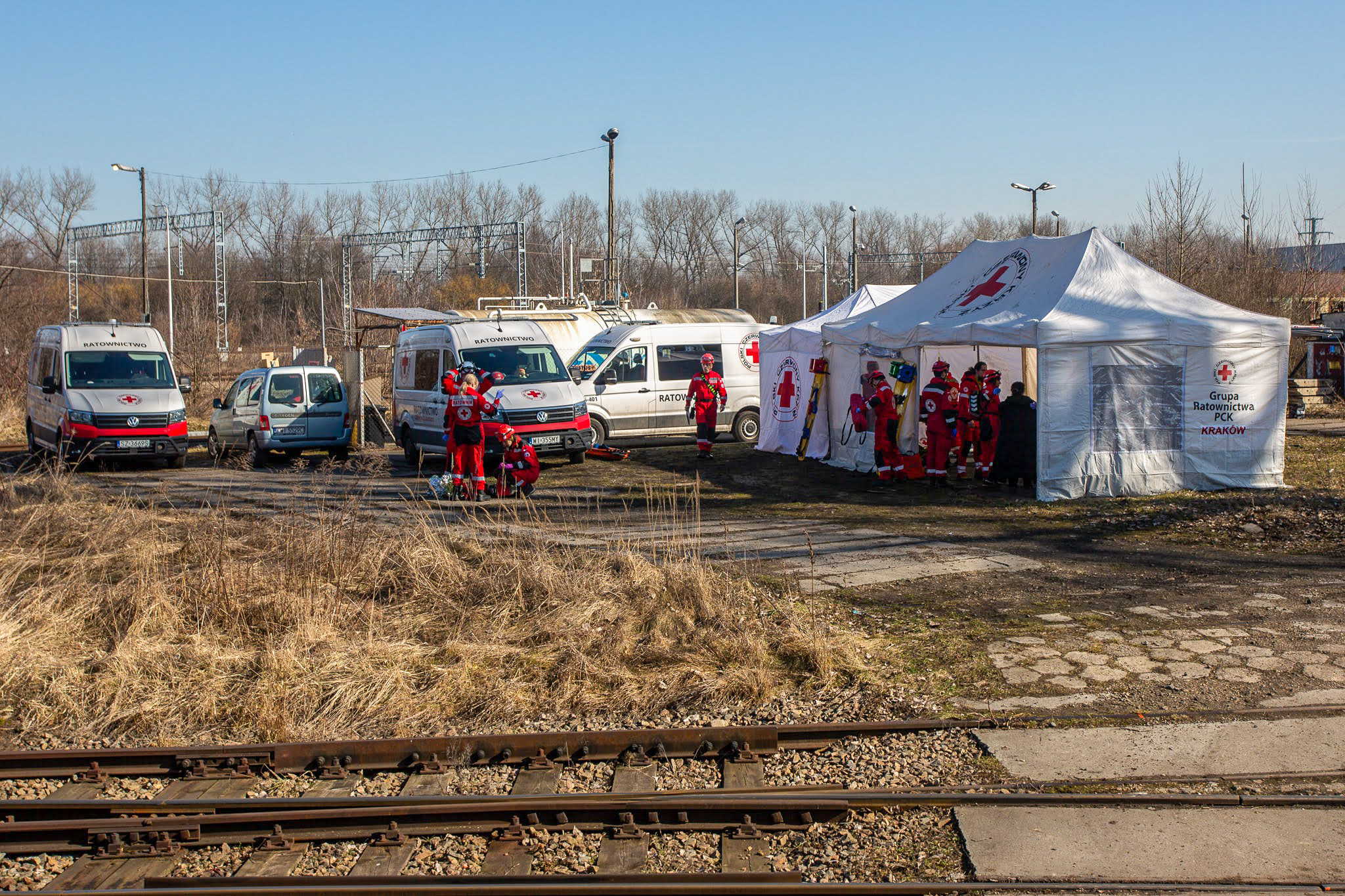 Zdjęcie przedstawia namiot polowy medyczny rozstawiony przy torach kolejowych