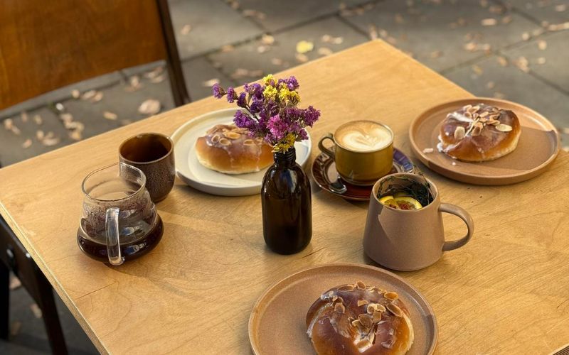 Zdjęcie przedstawia stolik, na którym znajduje się filiżanka kawy z ciastem
