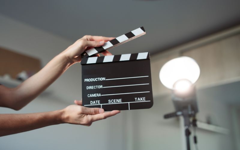 Zdjęcie przedstawia rękę, która trzyma klaps reżyserski