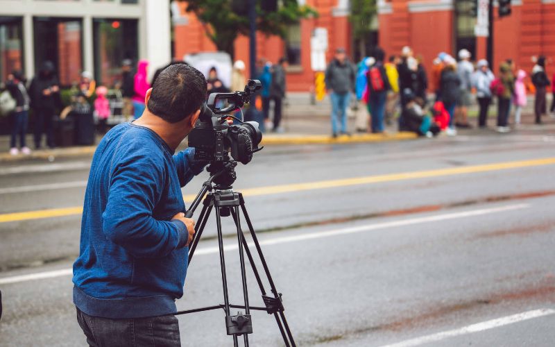 Zdjęcie przedstawia osobę, która kręci film w przestrzeni publicznej