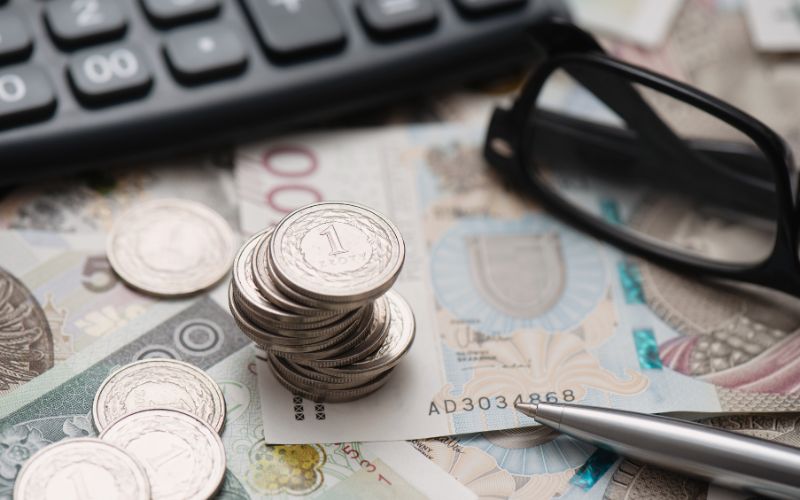 Zdjęcie przedstawia pieniądze w walucie polskiej obok których leży kalkulator i okulary