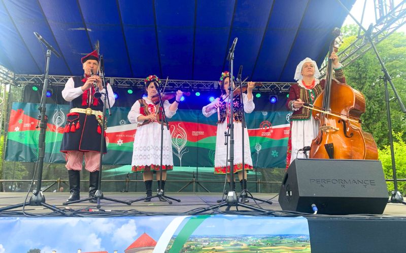 Zdjęcie przedstawia kapelę ludową na scenię, którzy grają na instrumentach