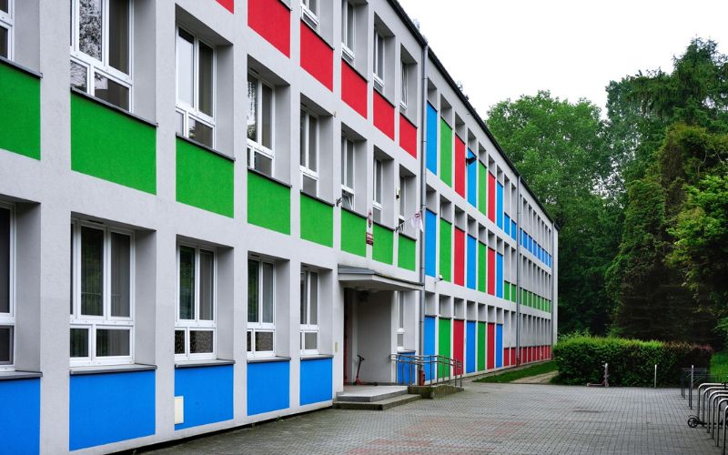 Zdjęcie przedstawia budynek szkoły z kolorową elewacją