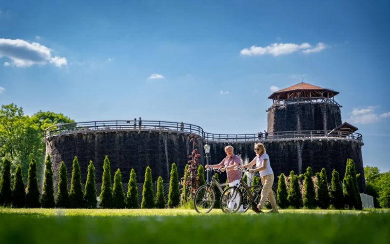 Dwie kobiety na rowerach przed budynkiem tężni solankowej w Wieliczce