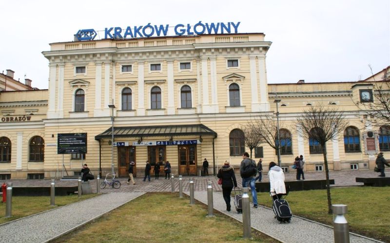 Zdjęcie przedstawia budynek Kraków Główny przed którym stoją ludzie