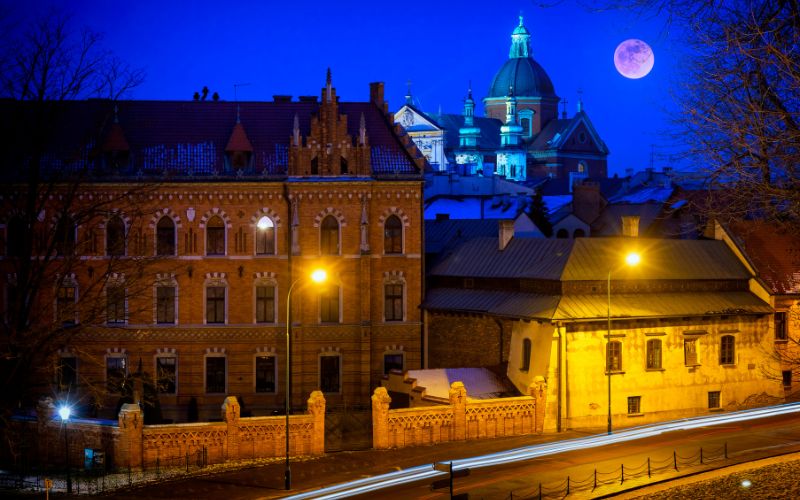 Zdjęcie zrobione jest nocą i przedstawia budynki Krakowa
