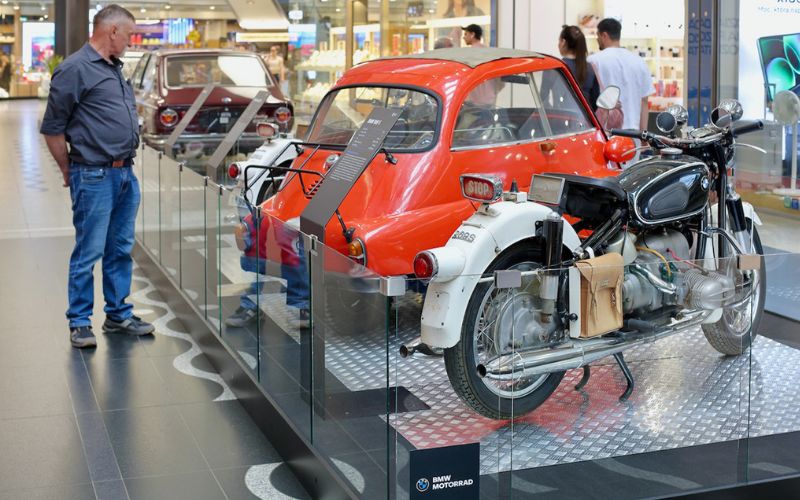 Zdjęcie przedstawia Pana, który ogląda wystawę motocykli i samochodów BMW